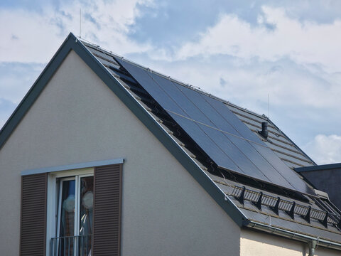 germany, newly built modern house with photovoltaic modules on roof under clear summer blue sky representing efficient renewable residential energy solutions