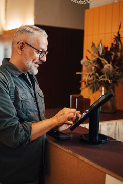 Smiling male entrepreneur using kiosk to register at shared workspace