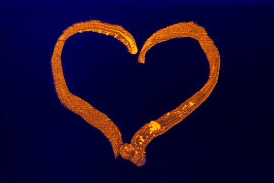 Neon orange heart marker glowing under ultraviolet black light