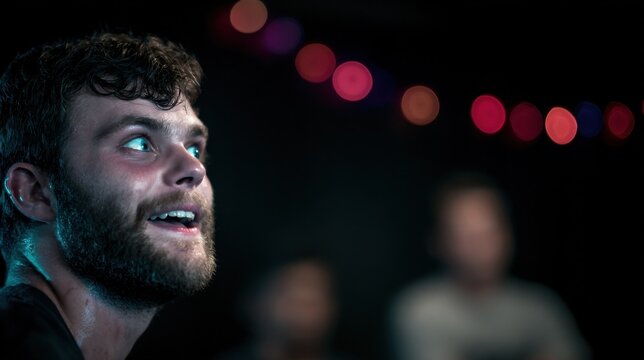 Closeup on a comedic improv actors animated face as they perform a scene with the blackbox studio setting and fellow performers subtly out of focus.