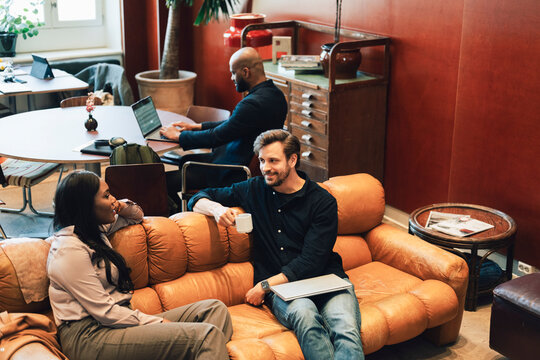 High angle view of male and female business professionals having conversation during coffee break at modern coworking sp