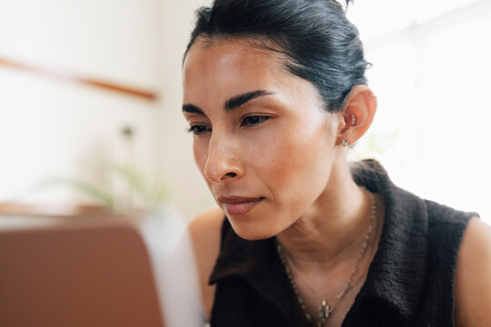 Close-up shot of focused businesswoman looking at her laptop screen while working at coworking space