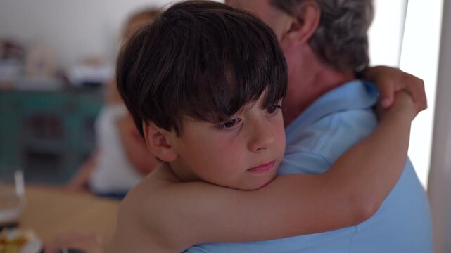 Boy hugging grandfather during family meal at home, highlighting emotional security, intergenerational love and family bonding