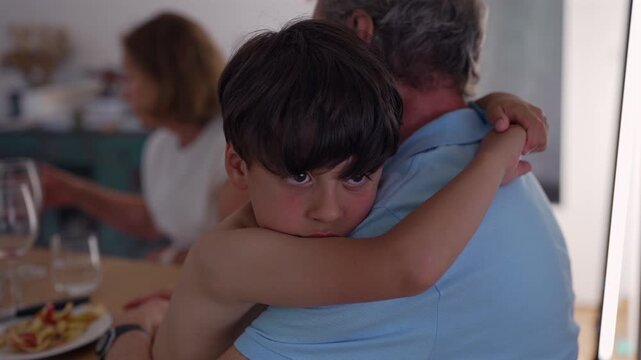 Boy seeking comfort from grandfather during family meal, highlighting emotional support, secure attachment and intergenerational connection