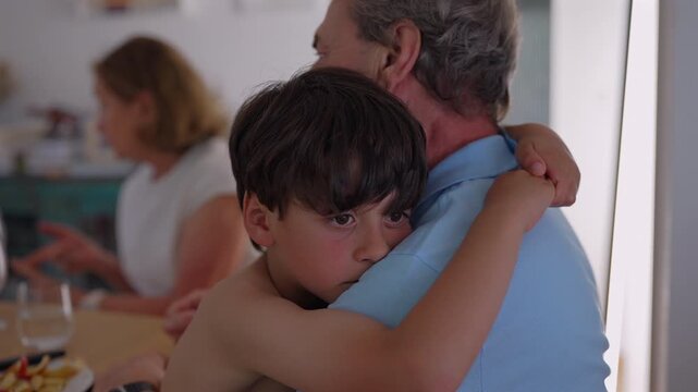 Thoughtful boy embraced by grandfather during family meal, highlighting emotional wellbeing, family connection and intergenerational care