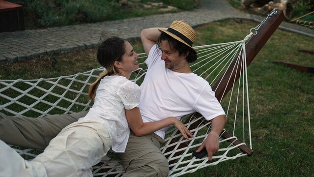 A loving couple relaxing in a hammock surrounded by nature, embracing a slower pace of life, genuine connection and the joy of being fully present with each other