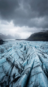 Textured blue glacier crevasses stretching under brooding stormy clouds