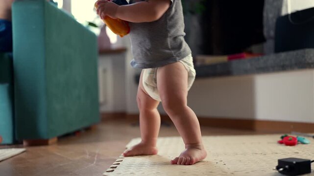 Toddler standing up while holding toy, highlighting gross motor development, early independence and childhood growth at home
