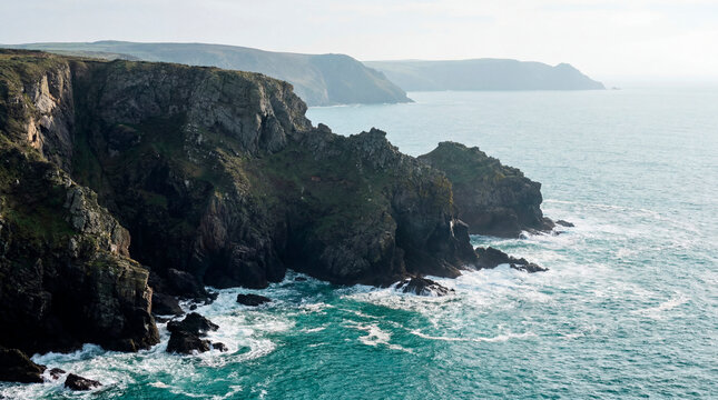 Rugged coastal cliffs and rocky headland meeting calm blue sea