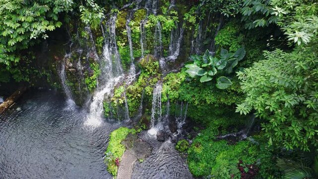 Drone view of waterfall with natural pool and lush tropical plants. Banyu Wana Amertha Waterfall in Bali.