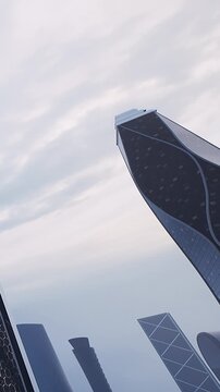 Tall buildings stand in a city, reaching high into the cloudy sky. Their shapes and designs reflect modern architecture and urban life. The scene captures a busy environment.