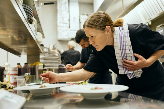 Female chef holding her dish towel while doing food presentation inside commercial kitchen