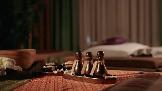 Massage oil bottles on tray beside massage table in spa interior.