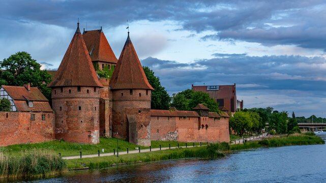 Medieval Teutonic Castle on the Nogat River in Malbork, Poland at dramatic cloudy sunset