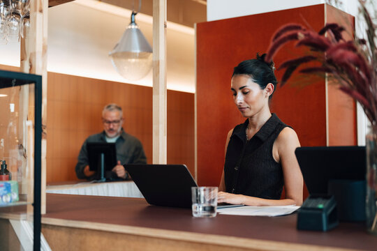 Focused female entrepreneur using laptop while working at modern coworking space