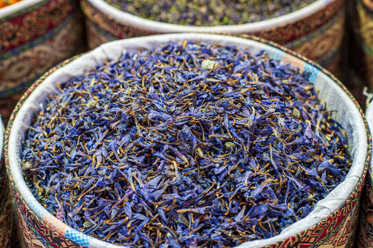Dried blue cornflower petals for herbal tea inside a traditional basket at a bazaar, Iran.