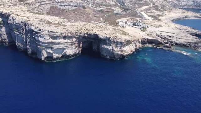 Aerial view of the rugged limestone cliffs and deep blue Mediterranean sea at Dwejra Bay on the coast of Gozo region, Malta. High quality 4k footage