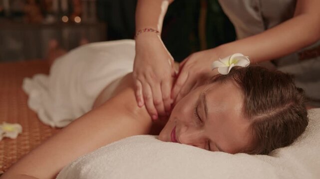 Slow motion woman receiving shoulder and back massage in spa treatment room with aroma oil.
