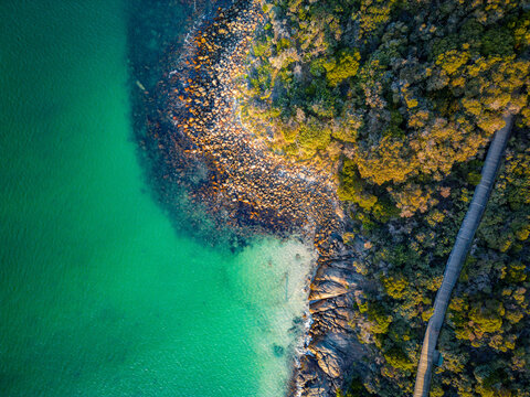 Aerial view of the turquoise waters and rocky coastline with a wooden boardwalk winding through coastal vegetation at Middleton Beach, Western Australia, Australia.