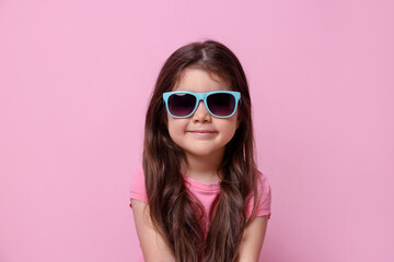 Fototapeta premium Cute little girl in sunglasses on pink background