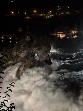 SCHAFFHAUSEN, SWITZERLAND - October 11, 2025: Tourist posing at Munot Fortress viewpoint overlooking the illuminated historic city of Schaffhausen after sunset on an autumn evening.