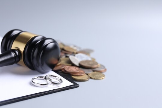 Alimony. Coins, gavel, clipboard and wedding rings on light background, closeup. Space for text