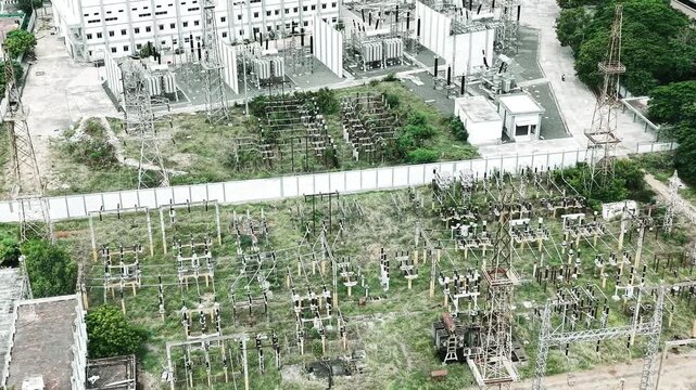 Overhead aerial video of a large electrical substation with transformer bays and gantry structure