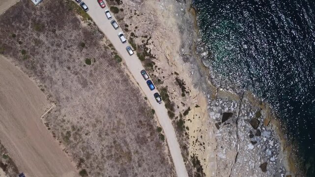 Salt Evaporation Ponds Off the Coast of Gozo, Malta. Xatt L-Ahmar. aerial view of a coastal road with sandy terrain and water body in a neutral. High quality 4k footage