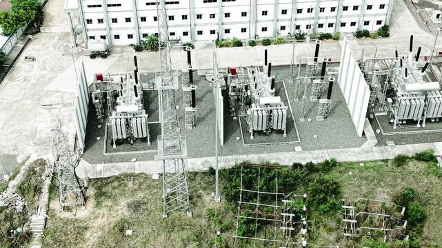 Close up aerial video of four large power transformers arranged in a row at a substation