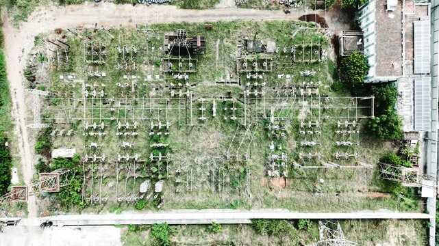 Drone video panning down over an electrical substation with transformers and switchyard equipment