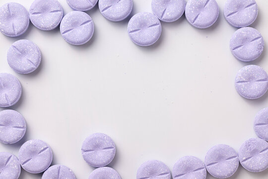 Large, round purple chewable tablets create a frame around sides of a white background.