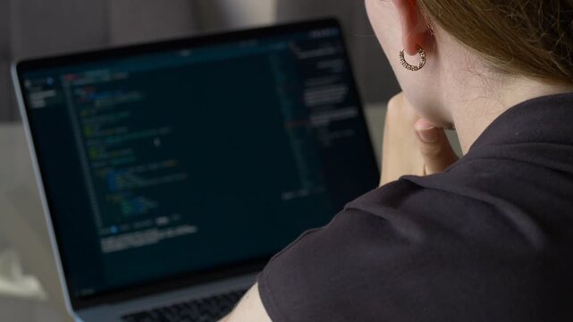 Woman thinking while looking at programming code on laptop with hand near face. Vibe coding, artificial intelligence assisted software development, focused problem solving and modern programming 