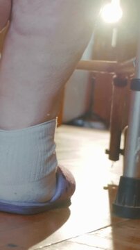 Elderly patient wearing a compression sock and slipper using a cane.