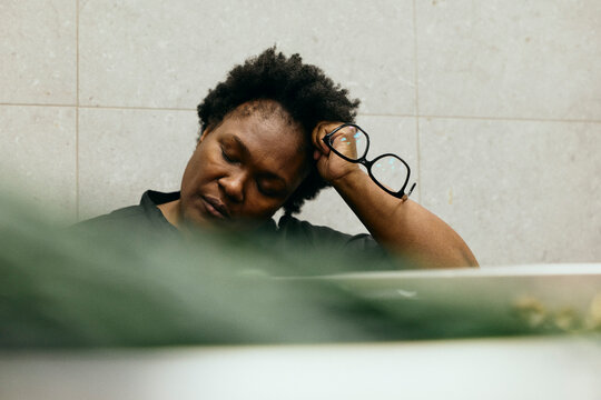 Tired female chef resting her head on arm while taking quick nap during shift