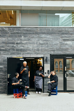 Group of kitchen staff taking coffee break outside restaurant building