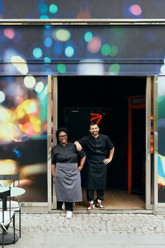 Two professional chefs in black uniforms standing at restaurant entrance