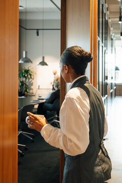 Businesswoman holding coffee while walking into conference room