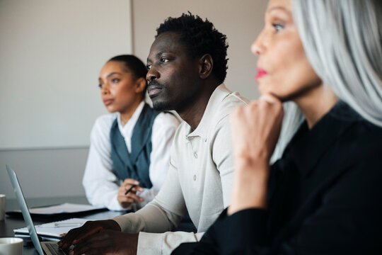 Group of diverse colleagues looking away thoughtfully during office presentation