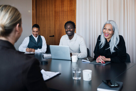 Diverse coworkers laughing during business presentation in office