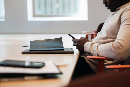 Midsection of businessman using smart phone in office meeting room