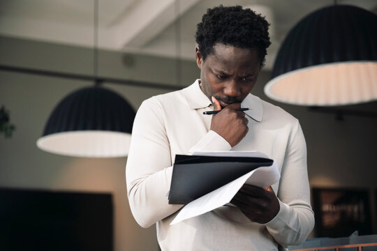 Thoughtful male business professional reviewing data while working at office