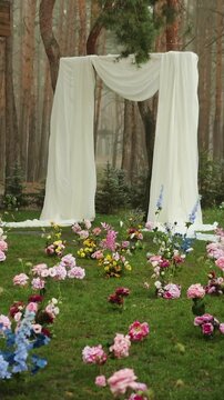 Vertical video. Wedding ceremony arch under heavy rain with white fabric decor during outdoor celebration.