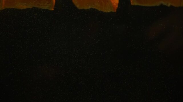 Orange slices falling into water with splashes on black background