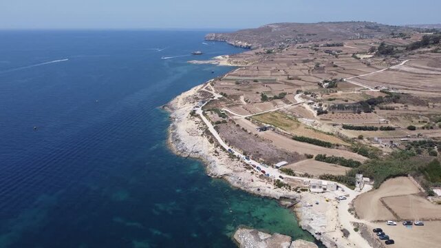 Ras il-Hobz salt pans, aerial shot , Gozo, Malta. serene aerial view of a coastal landscape with water and land, featuring blue and green hues and natural vegetation. High quality 4k footage