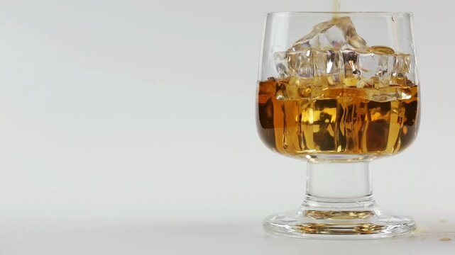 Cognac and alcohol are poured into a glass with ice on a white background