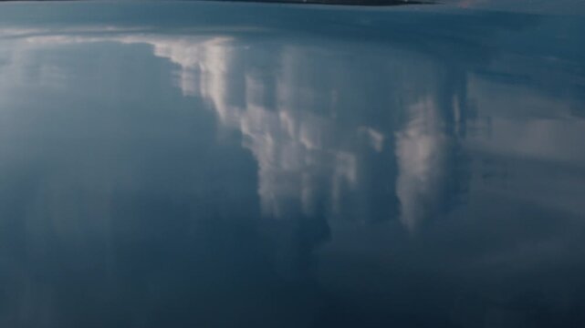 Calm water surface with reflection of the summer clouds