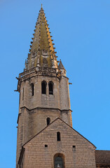 Fototapeta premium Tower and detail of front gable of Saint Philibert church with blue sky in the centre of the archdiocese Dijon, France