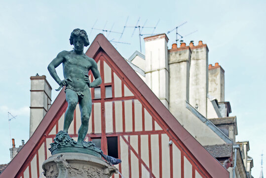 DIJON, FRANCE &ndash; APRIL 29, 2026: Bronze sculpture called 'The wine grape smasher', created by the artist Noel-Jules Girard, with half-timbered house in the back. Selective focus