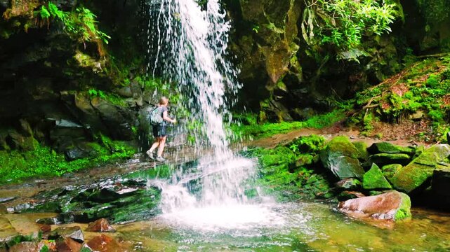 Female Hiker Walking Behind Grotto Falls In The Roaring  Fork Nature Area, Great Smoky National Park, Tennessee, USA
