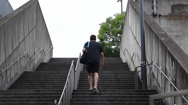 A man walks up a flight of concrete stairs.